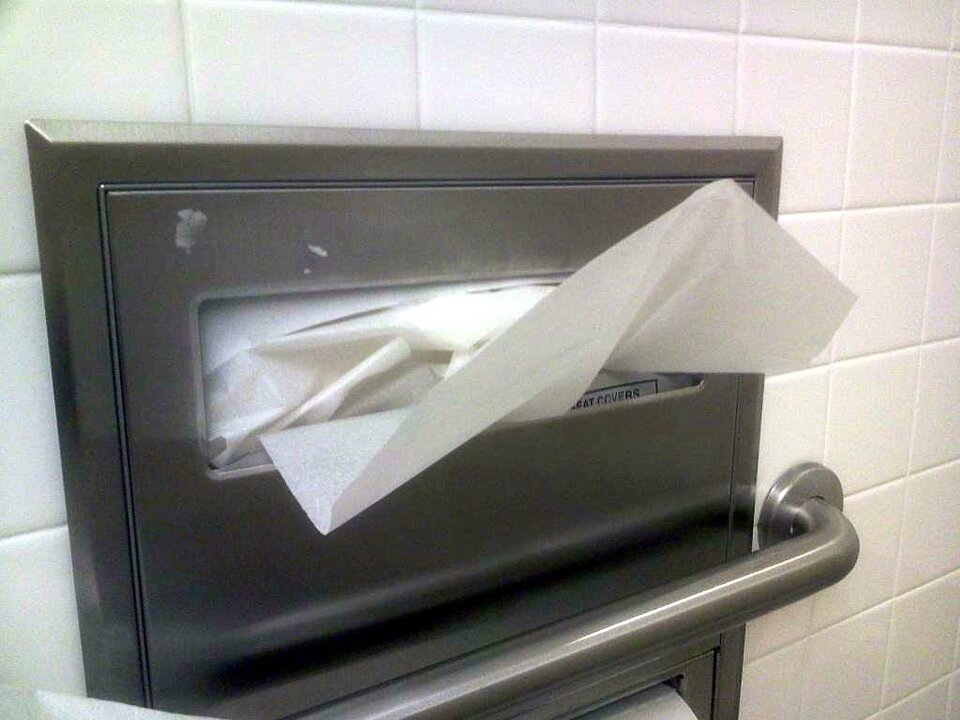 Ein Spender mit Einmal-Sitzbezügen hängt über beinahe jeder öffentlichen Toilette.